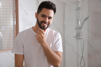 Photo of Handsome young man after shaving in bathroom, space for text