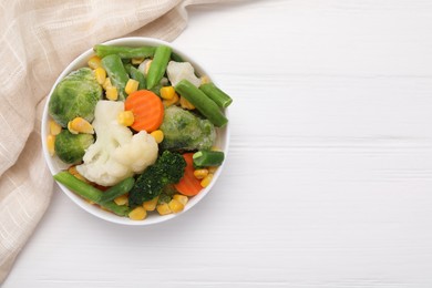 Photo of Mix of different frozen vegetables in bowl on white wooden table, top view. Space for text