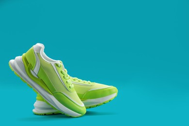 Photo of Pair of stylish green sneakers levitating on teal background, space for text
