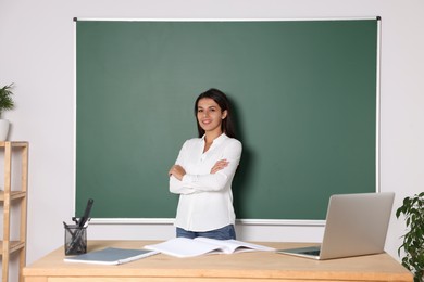 Photo of Happy young teacher giving lesson at blackboard in classroom. Space for text