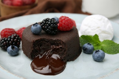 Photo of Delicious chocolate fondant served with fresh berries and ice cream on plate, closeup