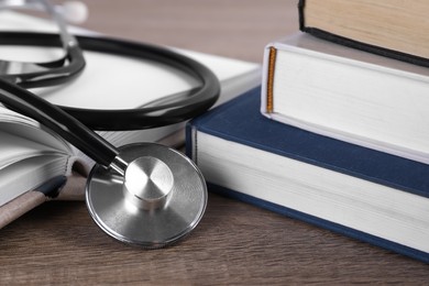 Photo of Student textbooks and stethoscope on wooden table, closeup. Medical education