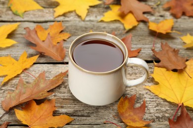 Photo of Cup of hot tea and autumn leaves on wooden table