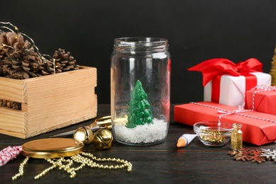 Photo of Composition of instruments and materials for snow globe on black wooden table