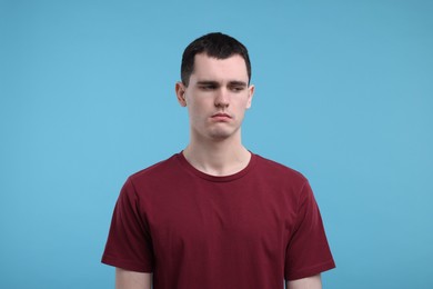 Portrait of sad man on light blue background