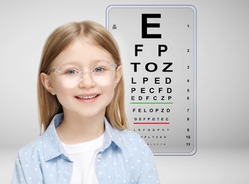 Vision test. Cute little girl in glasses and eye chart on grey background