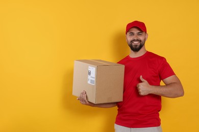 Photo of Courier holding cardboard box on yellow background, space for text