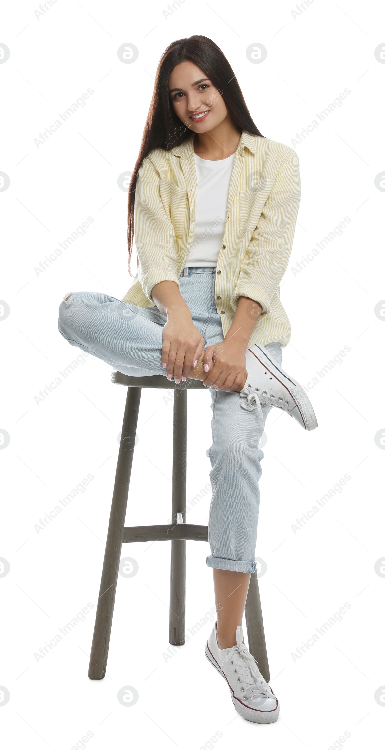 Photo of Beautiful young woman sitting on stool against white background