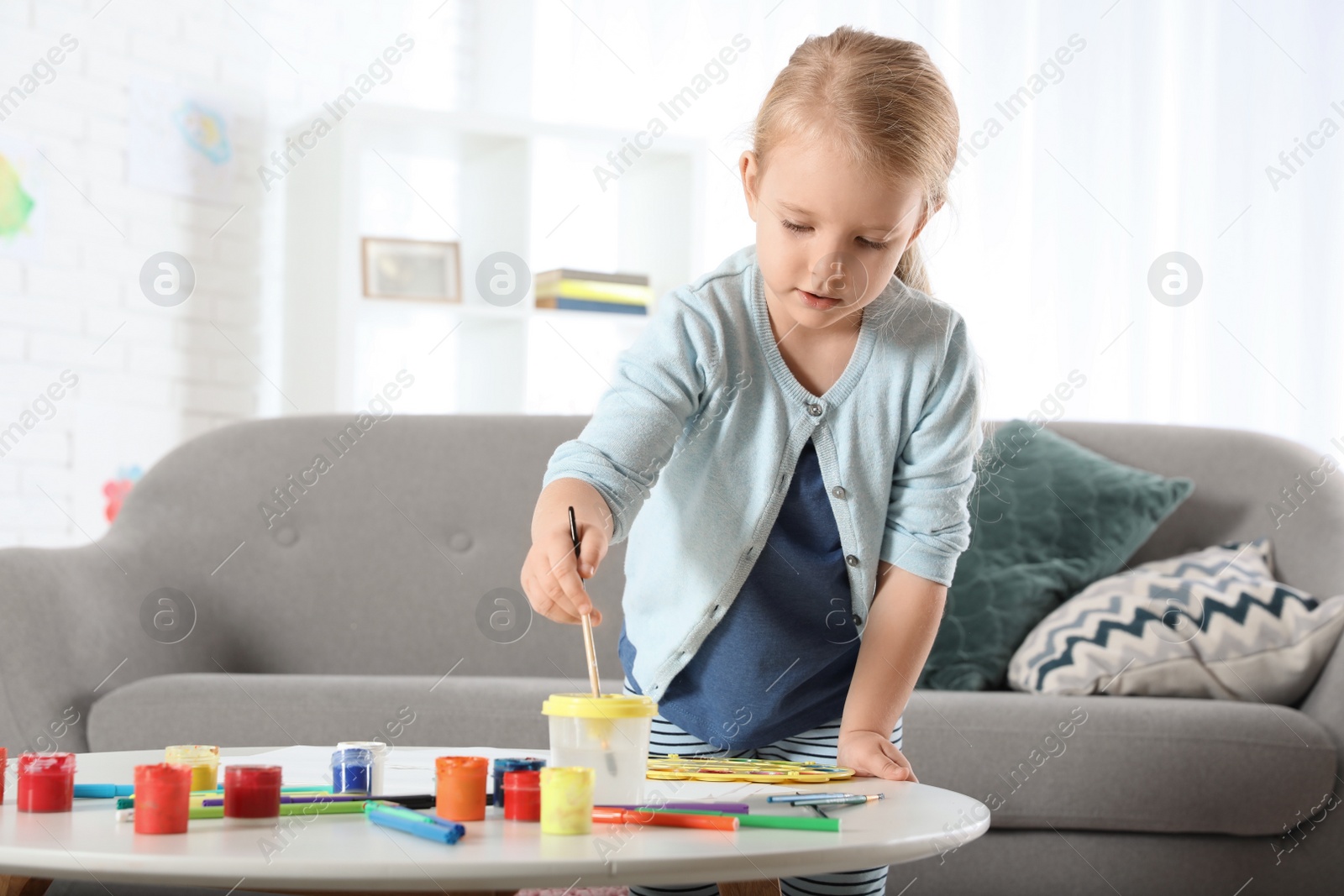 Photo of Cute little child painting at table indoors