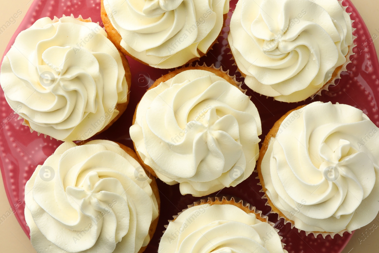 Photo of Tasty vanilla cupcakes with cream on beige background, flat lay