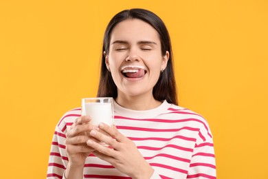 Photo of Happy woman with milk mustache holding glass of tasty dairy drink on yellow background