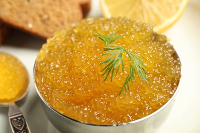 Fresh pike caviar in bowl, lemon and bread on table, closeup