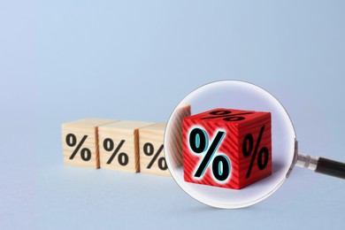 Image of Best mortgage interest rate. Red cube with percent sign among wooden ones on light background, view through magnifying glass