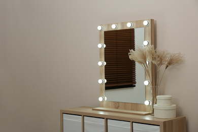 Modern mirror with lamps near beige wall in room