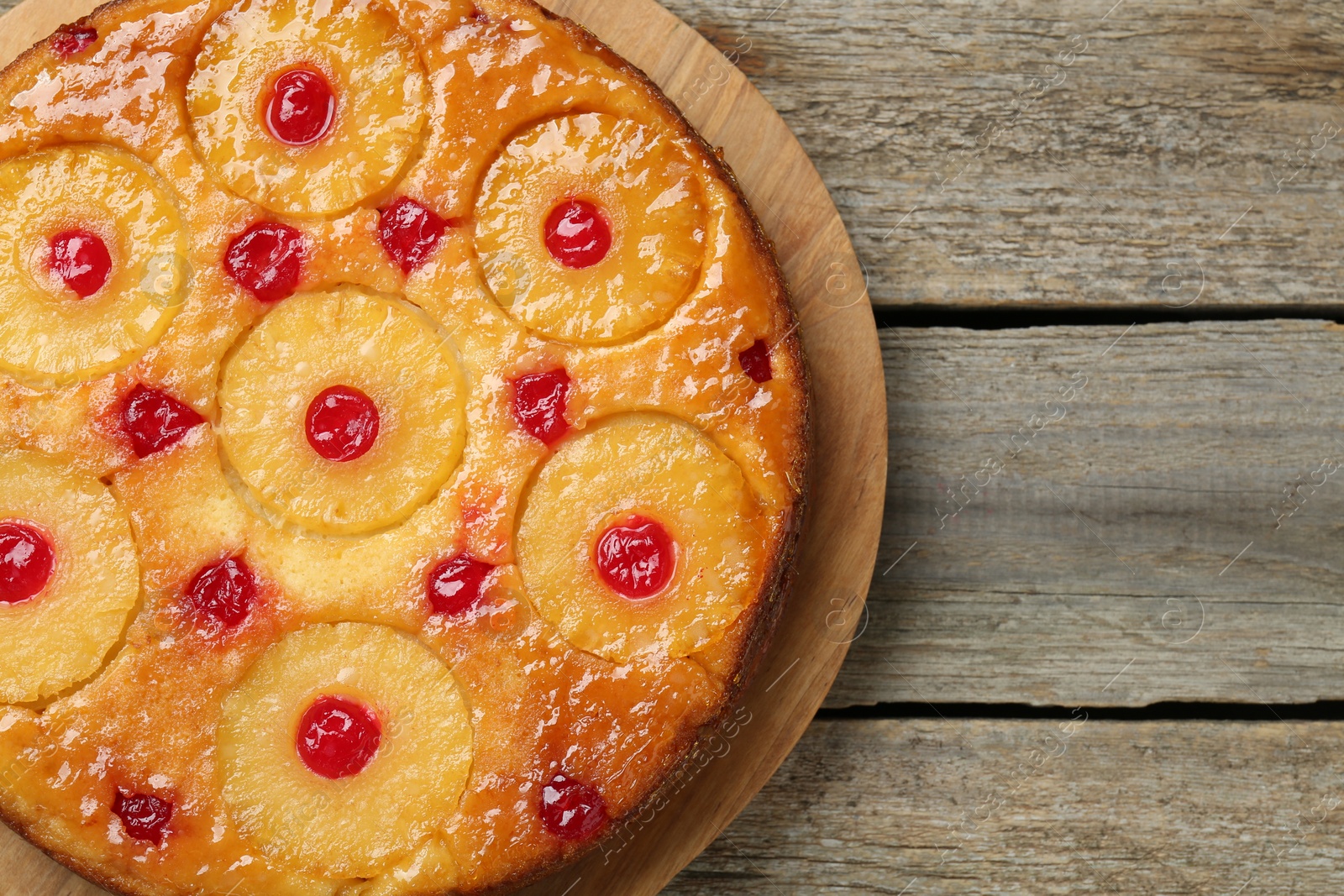 Photo of Tasty pineapple cake with cherries on wooden table, top view. Space for text