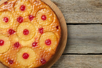Photo of Tasty pineapple cake with cherries on wooden table, top view. Space for text