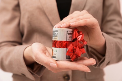 Photo of Woman holding bundle of dollars tied with ribbon, closeup