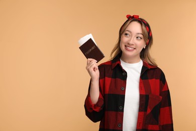 Happy young woman with passport and ticket on beige background, space for text
