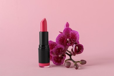 Beautiful lipstick and orchid flowers on pink background