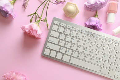 Flat lay composition with keyboard and flowers on pink background. Beauty blogger's workplace