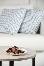 Photo of Aromatic potpourri of dried flowers in plate on white table indoors