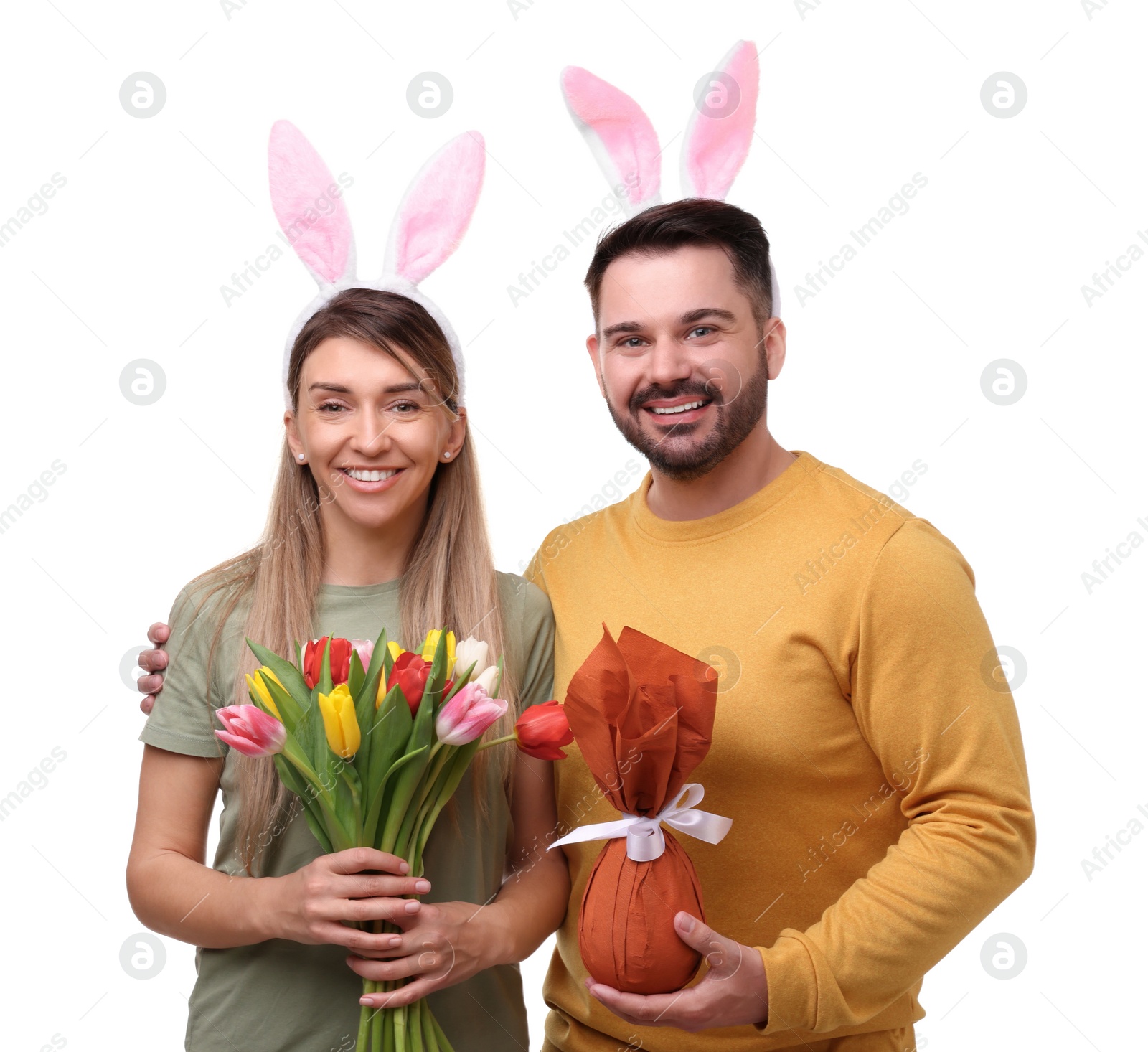 Photo of Easter celebration. Happy couple with bunny ears, tulip flowers and wrapped egg isolated on white
