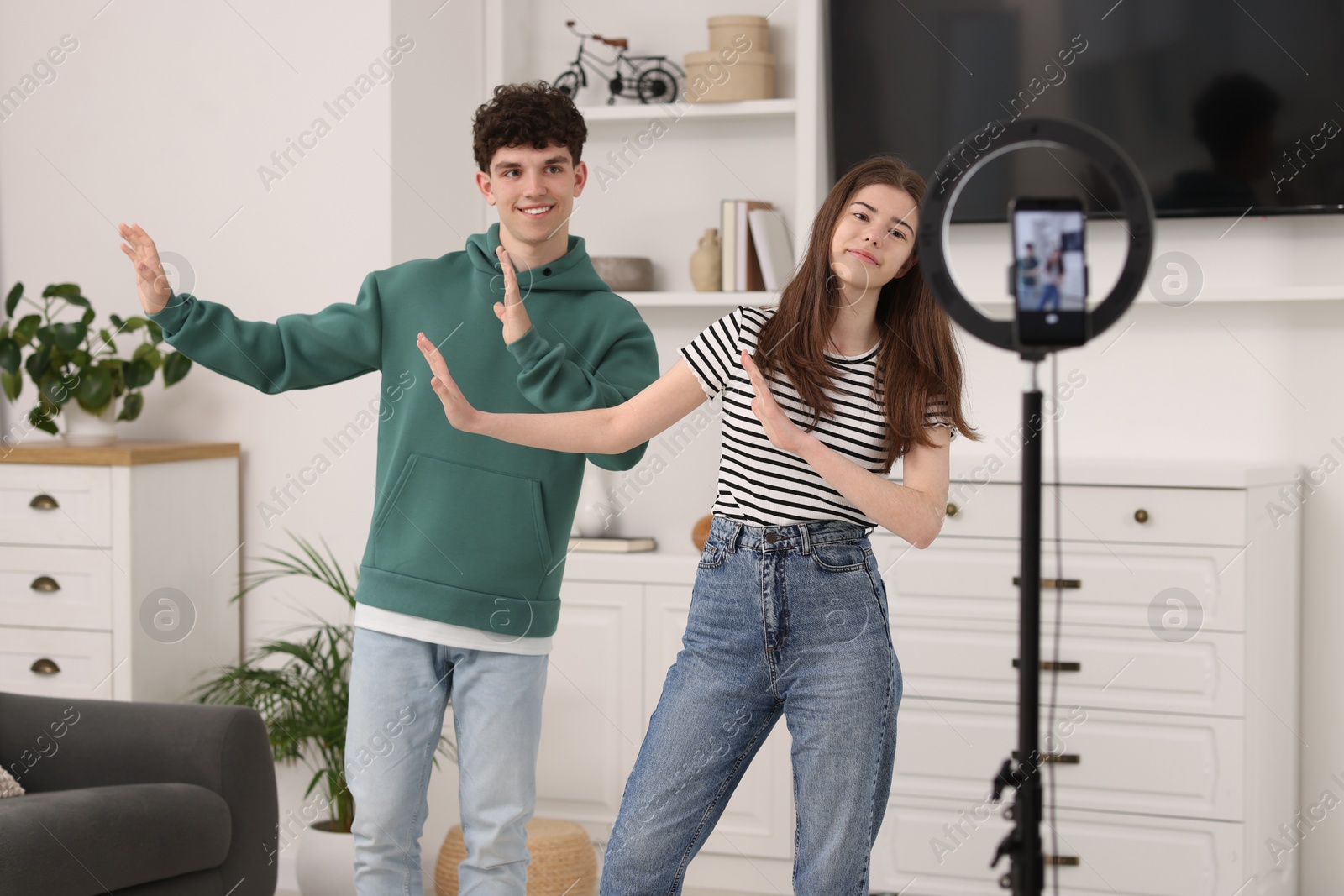 Photo of Smiling teenage bloggers dancing while streaming at home