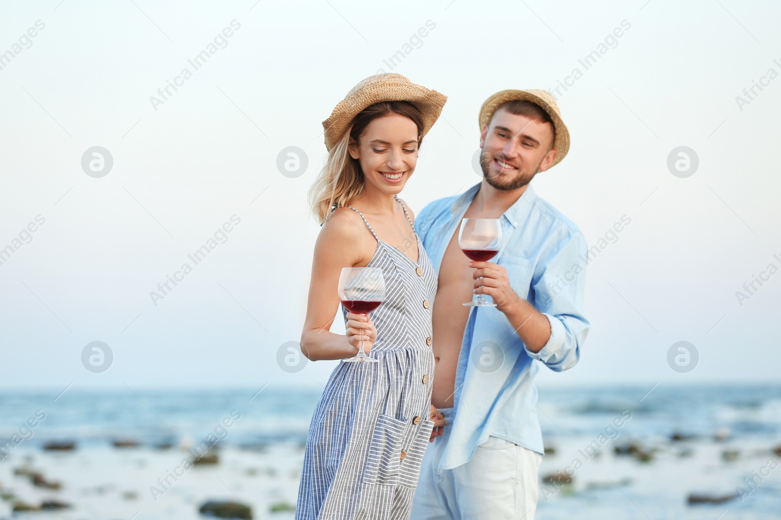 Photo of Young couple with glasses of wine on beach