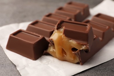 Tasty sweet chocolate bars with paper wrap on grey table, closeup