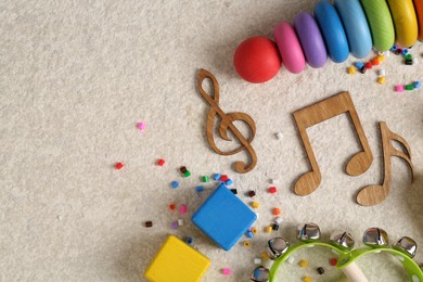 Photo of Baby song concept. Wooden notes, kids musical instruments and toys on beige carpet, flat lay. Space for text