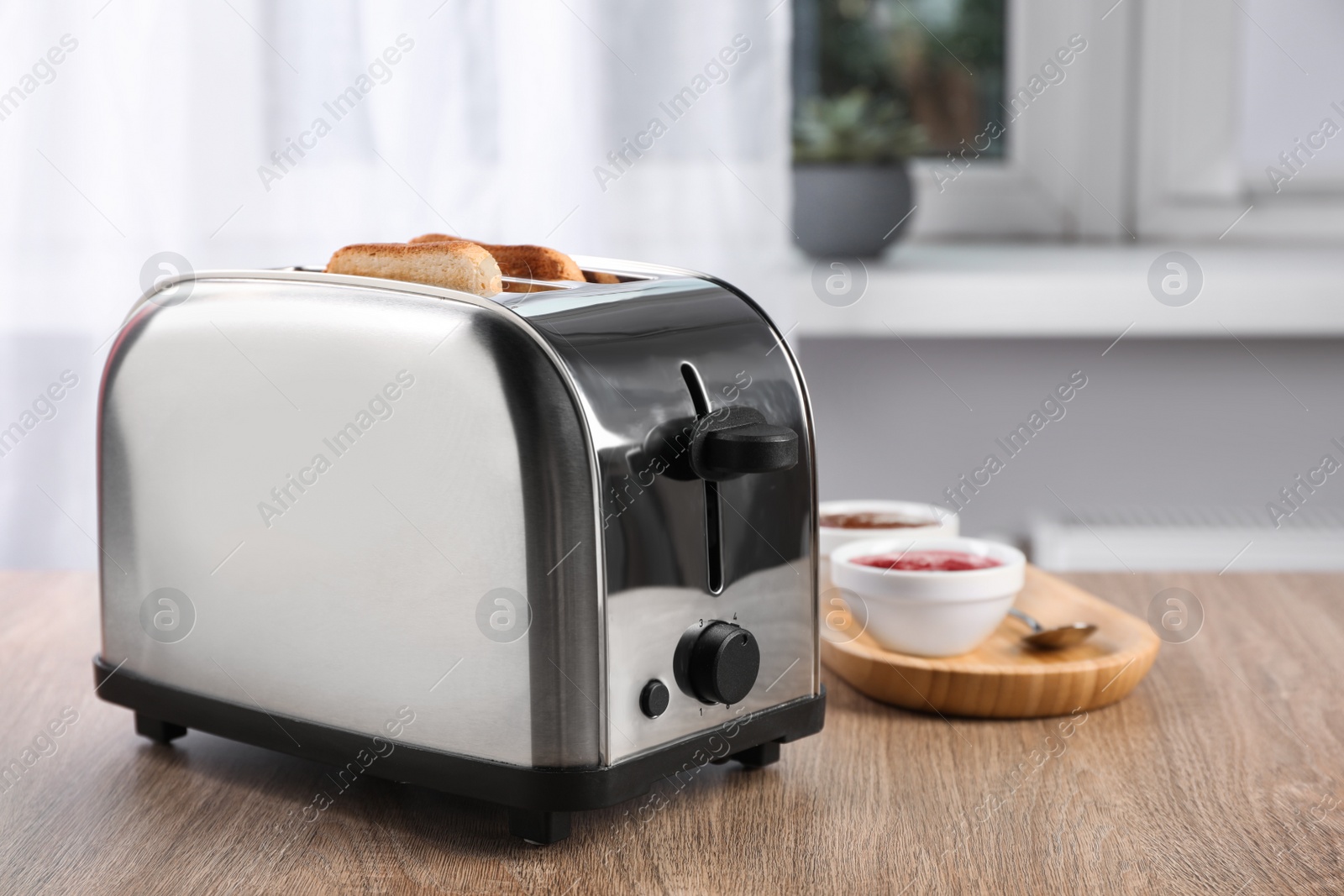 Photo of Toaster with roasted bread and jam on wooden table, space for text