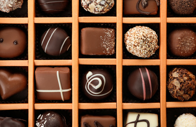 Photo of Box with different chocolate candies as background, top view