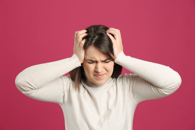 Photo of Young woman suffering from migraine on crimson background