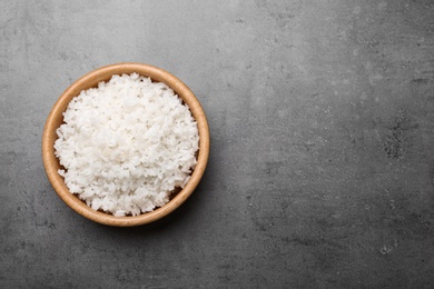 Bowl of boiled rice on color background, top view with space for text