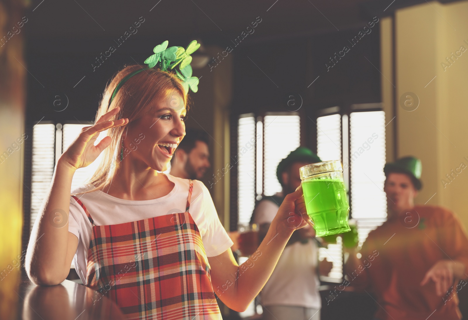 Photo of Young woman with glass of green beer in pub. St. Patrick's Day celebration