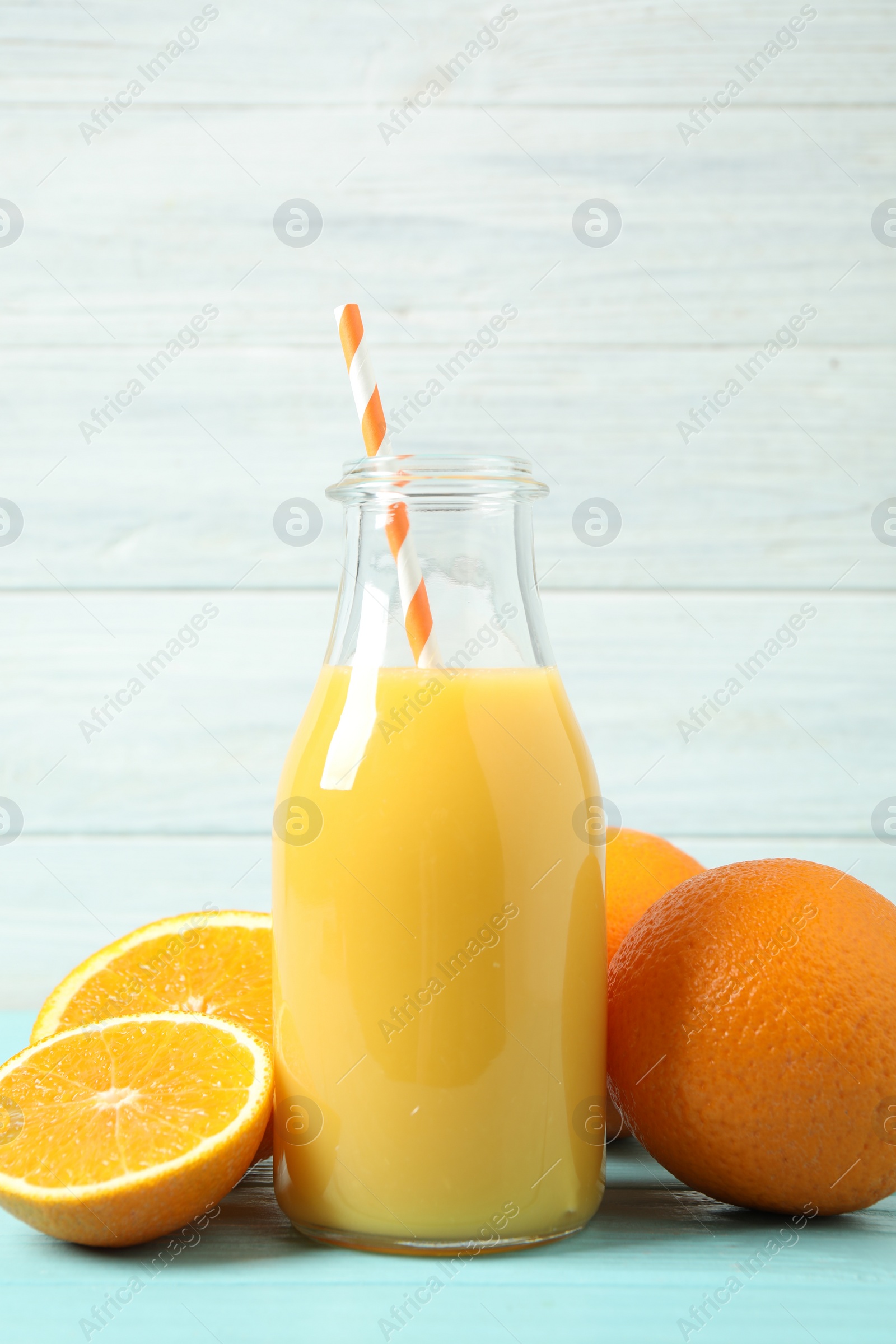 Photo of Bottle of orange juice and fresh fruits on light blue wooden table