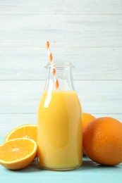 Photo of Bottle of orange juice and fresh fruits on light blue wooden table