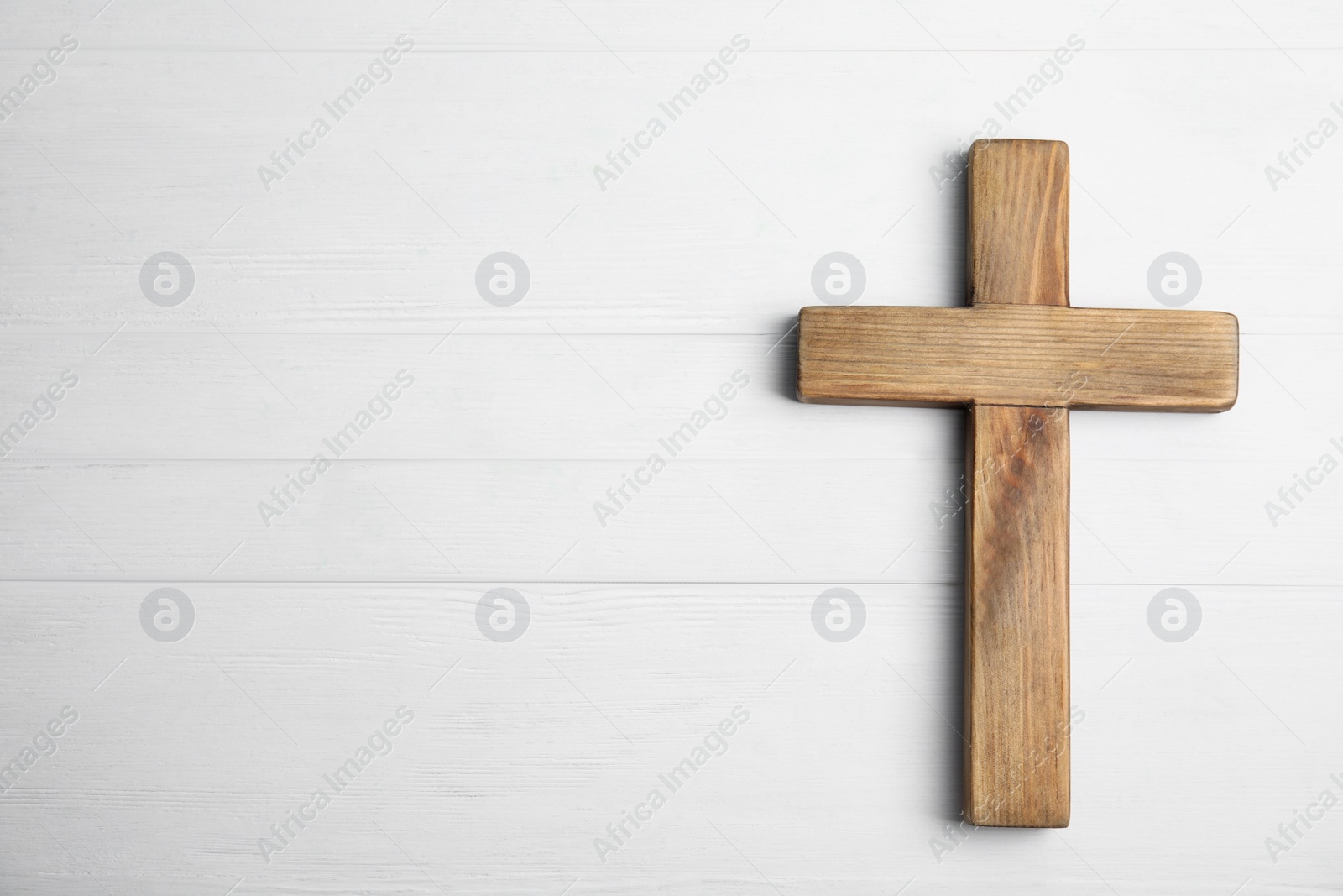 Photo of Christian cross on white wooden background, top view with space for text. Religion concept