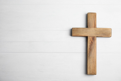 Photo of Christian cross on white wooden background, top view with space for text. Religion concept