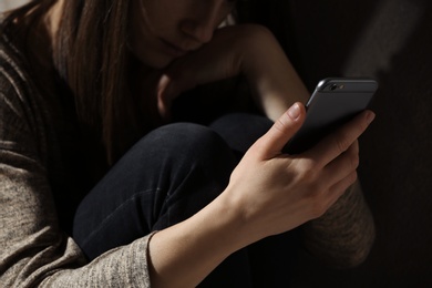 Woman using smartphone in dark room, closeup. Loneliness concept