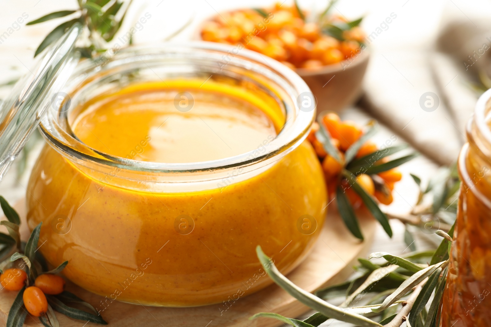 Photo of Delicious sea buckthorn jam and fresh berries on table, closeup