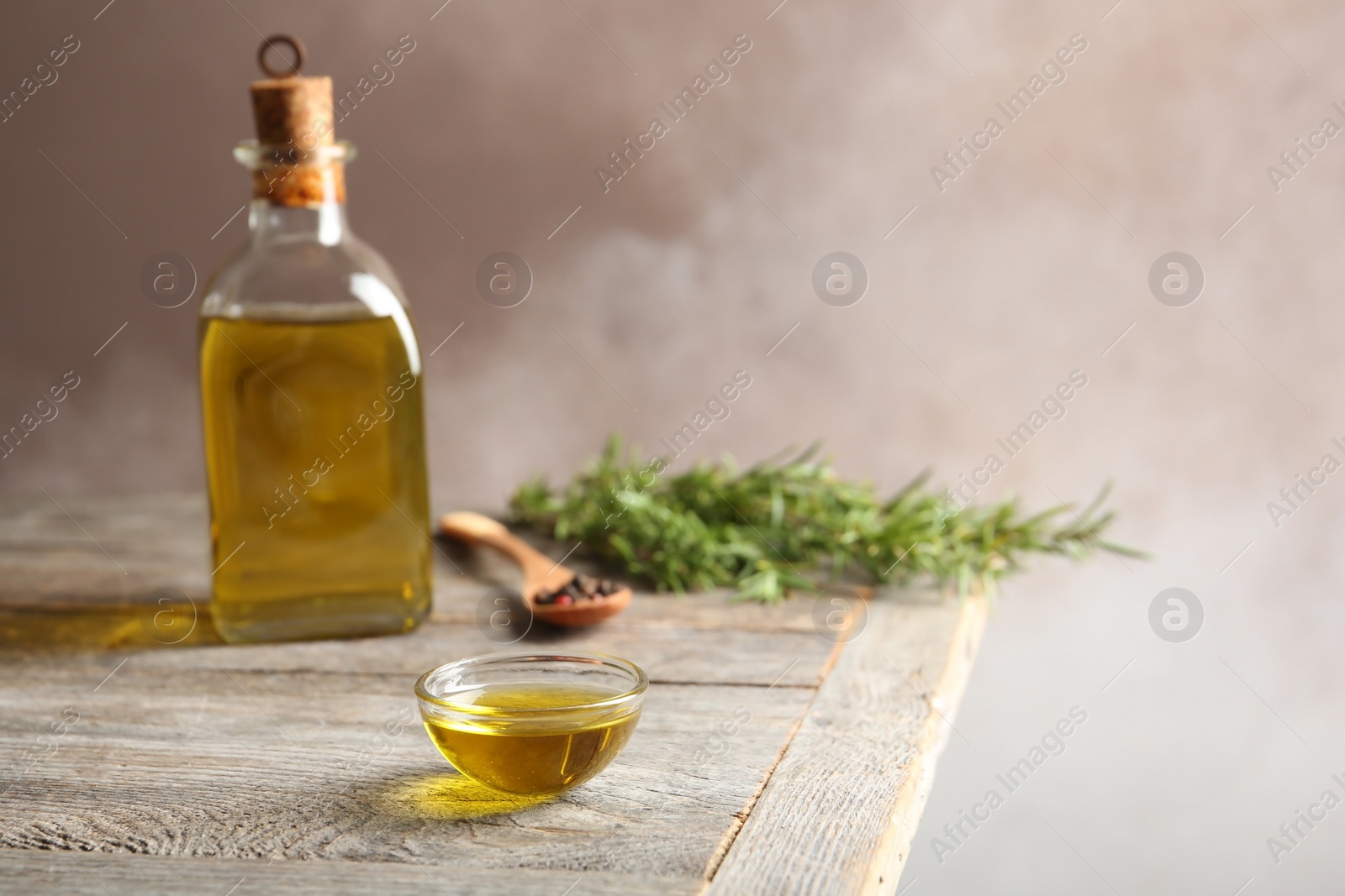 Photo of Bowl of rosemary oil on wooden table