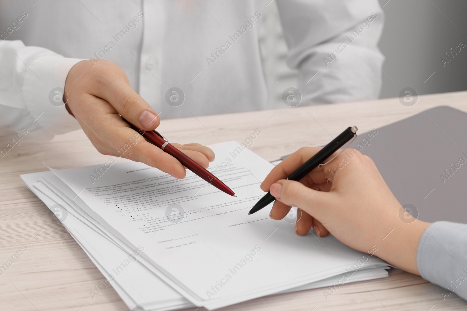 Photo of Man pointing at document and woman putting signature at wooden table, closeup