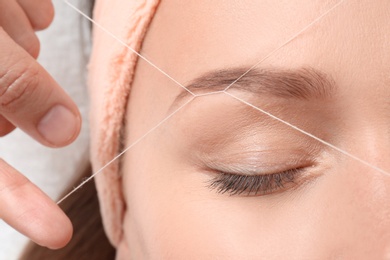 Photo of Young woman having eyebrow correction procedure in beauty salon, closeup
