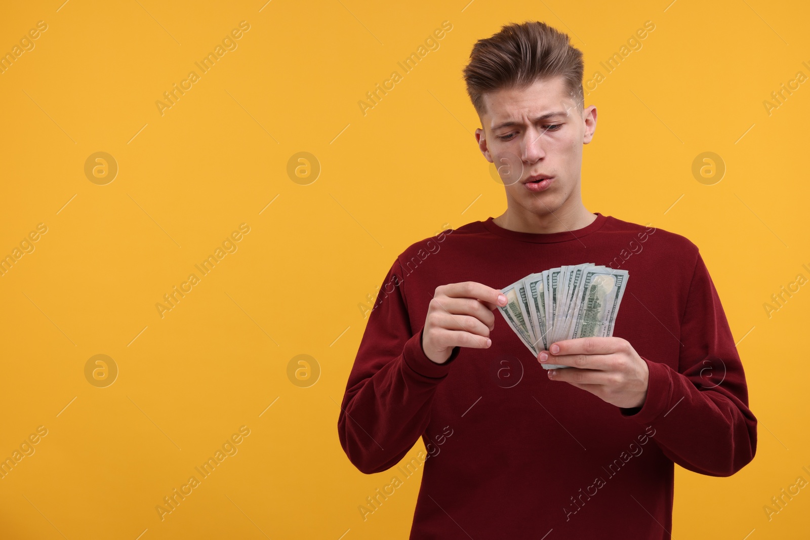 Photo of Handsome man with dollar banknotes on yellow background. Space for text