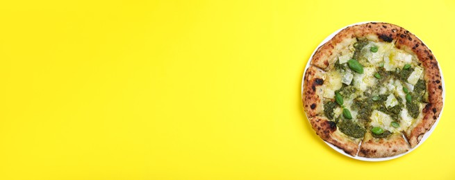 Delicious pizza with pesto, cheese and basil on yellow background, top view with space for text. Banner design