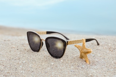 Stylish sunglasses and starfish on sandy beach