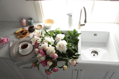 Photo of Beautiful peonies and breakfast on kitchen counter, above view