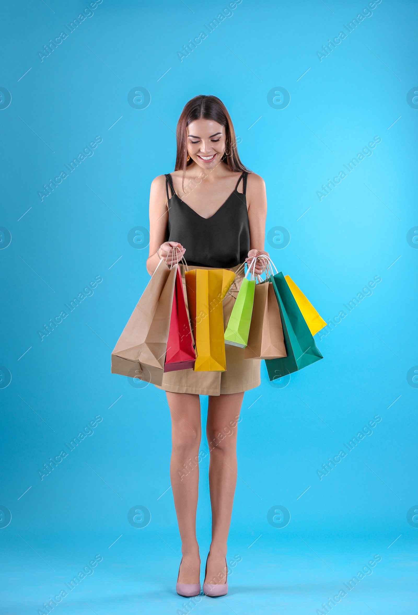 Photo of Young woman with shopping bags on color background