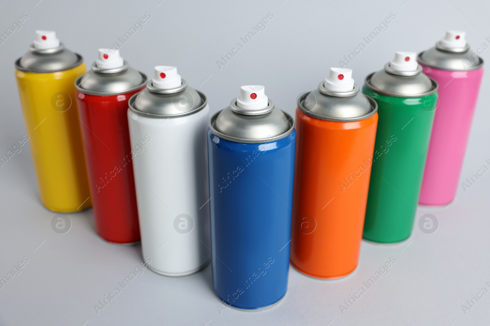 Photo of Colorful cans of spray paints on light grey background